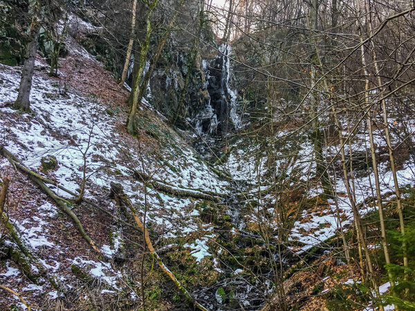 Frozen waterfall with icicles and a bit of streaming water in a forest landscape of Wasserfall Germany