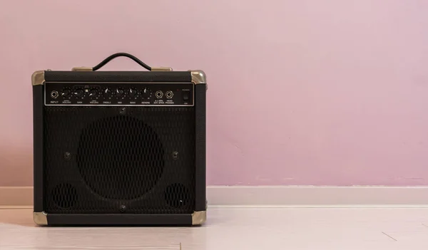 portable electric guitar amplifier isolated in front of a stone wall, music equipment background