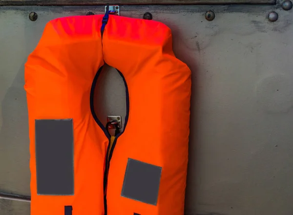 Jaqueta de vida laranja típico pendurado em uma parede de metal, segurança de transporte de água, fundo marinho — Fotografia de Stock