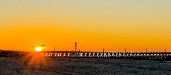 Hosszú móló naplementekor Blankenberge strandján, Belgium, naplemente színes égbolttal — Stock Fotó