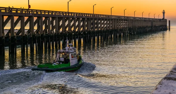 Small boat sailing in the harbor of Blankenberge, Belgium, view on the pier and lighthouse at sunset — Stock Photo, Image