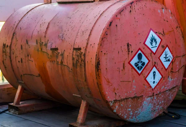 Viejo tanque de silo oxidado que contiene sustancias peligrosas, etiquetas de advertencia en el lateral, almacenamiento de líquidos peligrosos Imagen De Stock