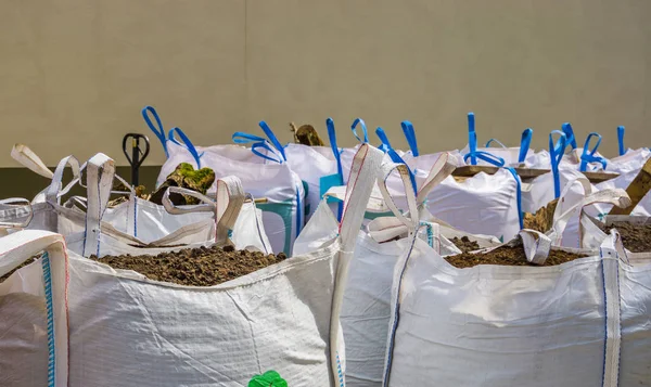 Bolsas grandes blancas llenas de tierra para macetas, horticultura e industria agrícola, fondo logístico — Foto de Stock