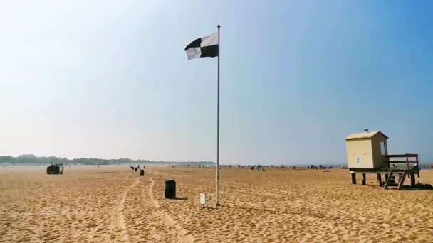 der Strand von vrouwenpolder mit einer schwarz-weiß karierten Flagge, die im Wind weht, Wassersport erlaubt, touristisches Küstendorf in Zeeland, den Niederlanden
