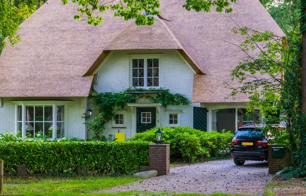 A frente de uma casa holandesa clássica com calçada, casa luxuosa na floresta, casa vintage com um telhado de palha — Fotografia de Stock