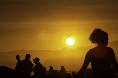 Arka planda bir gün batımı ile insan siluetleri