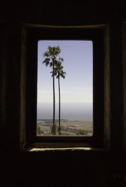 Palmiye ağaçları ve okyanusun kalenin pencereden görünümü
