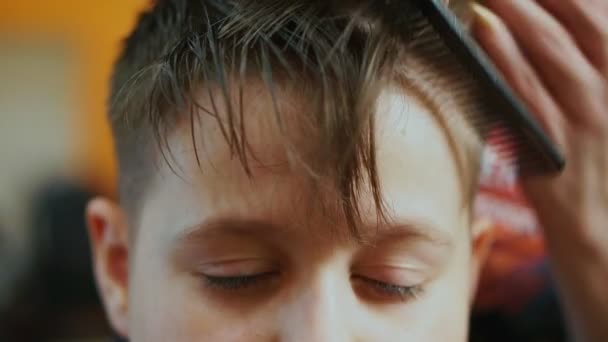 Closeup of the hand of a woman hairdresser shearing a boy. The hair falls down, the boys eyes fall asleep — Stock Footage Closeup of the hand of a woman hairdresser shearing a boy. The hair falls down, the boys eyes fall asleep Royalty Free Stock Video