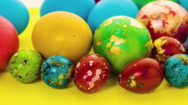 Çok renkli çok renkli Paskalya yumurtaları açık sarı ve pembe arkaplanda serpilmiştir. Küçük ve büyük boyalı Paskalya yumurtaları. Paskalya için şenlik dekorasyonu.