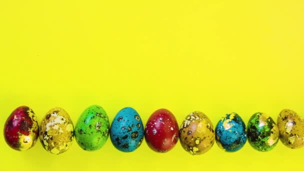 Sokszínű, gyönyörű húsvéti tojások sorakoznak sárga, fényes háttérrel. Ünnepi háttér húsvét. A szöveg helye.