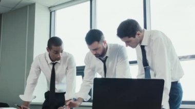 Üç işadamları, iki beyaz ve stend gömlek masada ve fırtınalı bir Afrika Milli takım proje, kağıtları çizelgeleri ile tartışın. İş takım çalışmalarını. Beyin fırtınası. Ofis panoramik pencerelere.