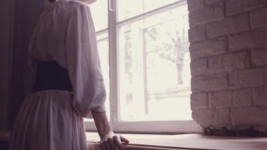 Güzel genç kız büyük cam kenarında duran, mesafe içine bakarak, düşünme. Stüdyo Oda doğal ışık ile. Yakın çekim yüz kız makyaj olmadan. Kız balerin önce eğitim ve dans.