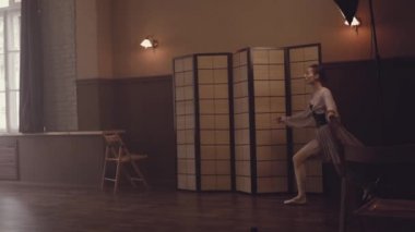 Balerin dans içinde atlama yapar ve sicim uzanır. Bale dans. Balerin havadar bir güzel zarif elbise ve Bale terlik yavaşça eski bir iç Studio büyük pencereler ile dans ediyor.