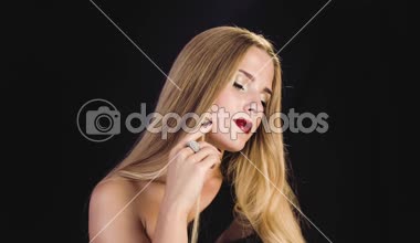 Profesyonel makyaj, kırmızı dudaklar ile uzun düz saç Studio siyah arka plan üzerine kameraya poz güzel genç kız. Küçük elmas ile büyük gümüş yüzük. Gösterir yüzük parmağına.