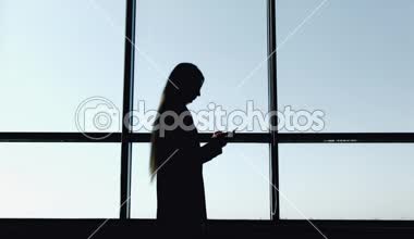 İş kadını ile smartphone içinde yazıhane ile büyük panoramik pencere silüeti. İş ve insan kavramı.