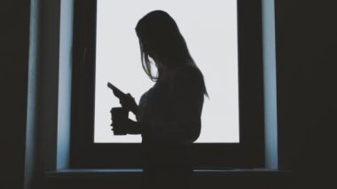 İş kadını ile smartphone pencere yakınındaki silüeti. İş ve insan kavramı.