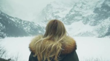 Kız sırtını kameraya karla kaplı dağlar arka plan üzerinde duruyor. Bir arka plan karlı Dağları'nın kız. Alpler kışın seyahat.