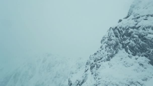 山の上に飛ぶ 美しい冬の山は 曇り霧の風の強い日に雪で覆われて 冬の南部の山々 の頂上に沿って霧の旅 — ストック動画
