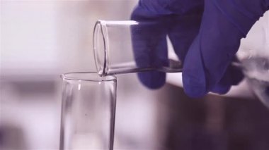 Laboratuvar çalışanı sıvı, su, kompozisyon bir Flask diğerine dışarı çıkar. Ölçme camına içki döktü. Laboratuarda analiz, araştırma için hazırlık.