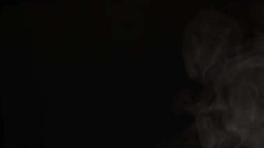 Esmer arka planda duman. Beyaz duman bulutu yavaşça yukarı doğru yükselir siyah bir arkaplana doğru. Dumanın etkisi.