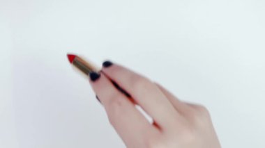 Kız Beyaz Kağıt arka plan Zigzag hatları üzerinde kırmızı bir ruj çizer. Ruj ile bir kadın el yakın çekim. Altın ucu ile ruj siyah tüp. Siyah çivi ile güzel kadın eller.