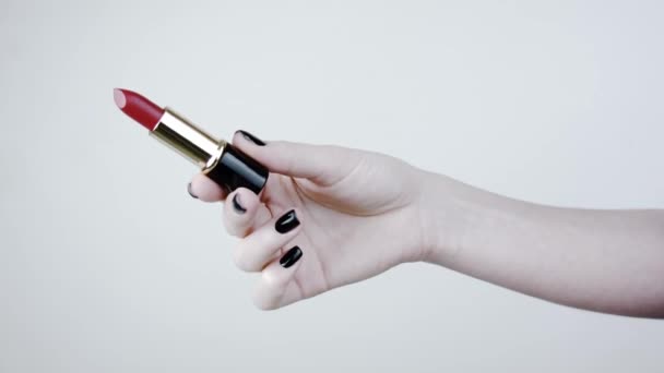 女人一手拿着红唇膏 美丽的女性手与黑色指甲 在白色背景的工作室 — 图库视频影像