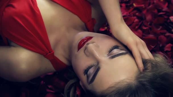 Девушка Красном Платье Красивой Прической Лежит Лепестках Красных Роз Медленно — стоковое видео