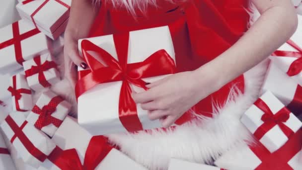 穿着红色衣服的快乐迷人的女人手里拿着礼物 高兴地看着礼品盒 被隔离在白色背景的工作室里 手头上的礼物 — 图库视频影像