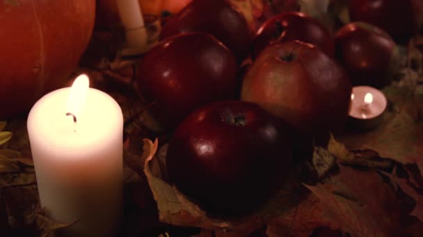 收获红苹果和干草放在秋天的枫叶上 为感恩节 万圣节 丰收节制作蔬菜 鲜花和燃烧的蜡烛 — 图库视频影像