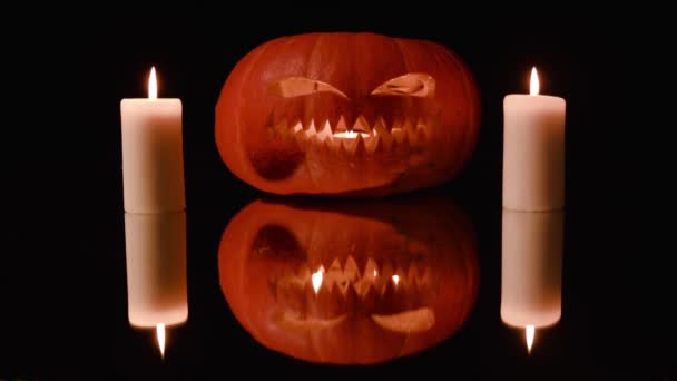 所有圣徒节 万圣节 南瓜与雕刻邪恶的脸和牙齿形状锯躺在镜子表面 大大小小的蜡烛燃烧周围和里面的南瓜 反射南瓜和蜡烛在镜子 — 图库视频影像