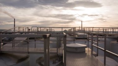 Bir endüstriyel şehrin arka plana karşı günbatımı. Fabrikanın çatısından resim. Bulutlar yükselen güneşin arka planına karşı boru Fabrikası ile şehir panoraması.