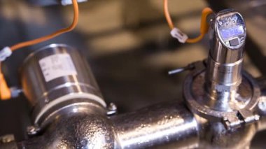 Gemiler tüpler ve borular ile modern bir bira fabrikası bira içinde elektronik basınç ölçer yakın çekim. Parlak yeni çelik borular. Metal üzerinde kondens.
