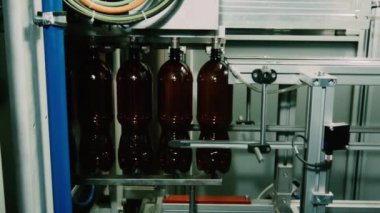 Bir bira fabrikasında otomatik dolum makinesi. Konveyör bandında bira için plastik şişeler. Sanayi için dolum makinesi.