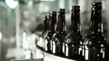 Bir bira fabrikasında otomatik dolum makinesi. Konveyör bandı üzerinde bira için cam şişeler. Sanayi için dolum makinesi.