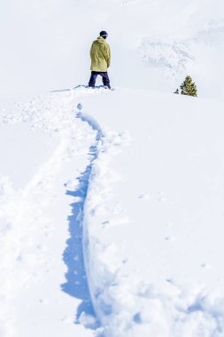  Snowboard rider waiting for a backcountry descent clipart