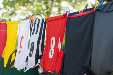 Çamaşır ipinde kurutmak için asılı renkli kıyafetler. Futbol formaları. 