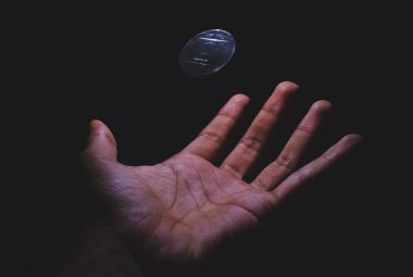 Bir el/palm tarafından denetlenen kayan yazı tura. 