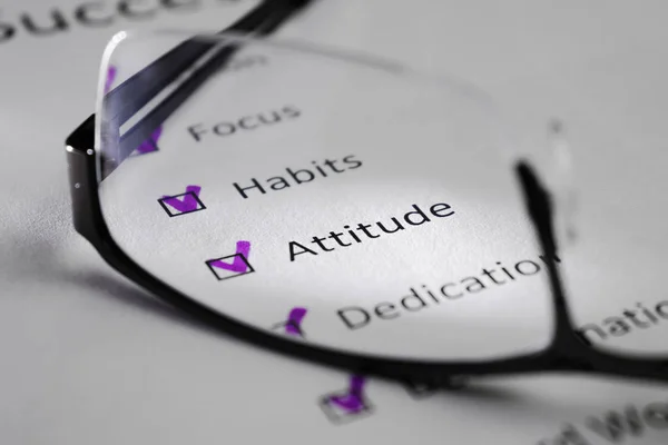 Beyaz bir levha üzerinde tutum yazıt. Bu bir motivasyon kontrol listesi ile başarı için puan var. Satırları siyah kareler onay işaretleri vardır. Resmi gözlük lens ile çekilen ve bir ışık huzmesi tarafından vurgulanan.