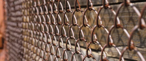 Old rusty metal mesh, vertical wooden planks beneath it — Stock Photo, Image