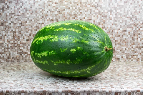 Mutfak masasında parlak çizgili yeşil bir karpuz. Güzel arkaplan