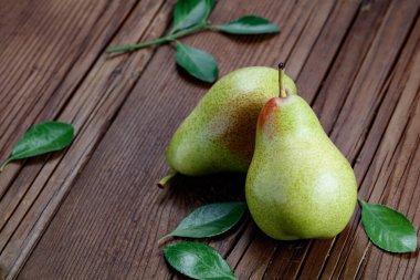 Ahşap arka planda yaprakları olan armutlar