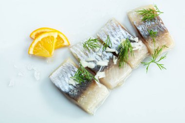 Beyaz arkaplanda limon ile servis edilen fileto ringa balığı.