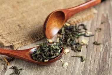 Yasemin çiçekli yeşil çay ve ahşap arka planda iki kaşık