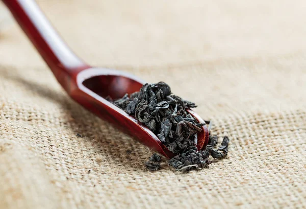 Czarna Herbata Liście Drewnianą Łyżką Tle Płótna — Zdjęcie stockowe