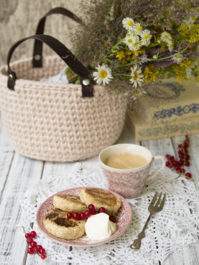 Kahve, ekşi krema ve bir buket çiçekler ve Kitaplar, portre, seçici odak ile arka plan üzerinde meyveleri ile ahşap bir masa üzerinde vintage plaka üzerinde yaz süzme peynir krep