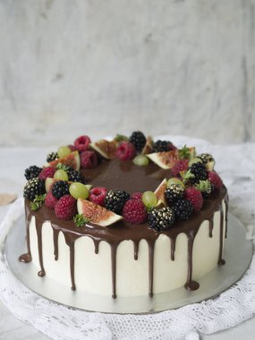 Kek beyaz krema, çikolata damlar ve mevsim meyveleri ve meyve: incir, üzüm, ahududu ve böğürtlen. Sonbahar ruh hali. Yakın çekim, uzay, seçici odak Kopyala