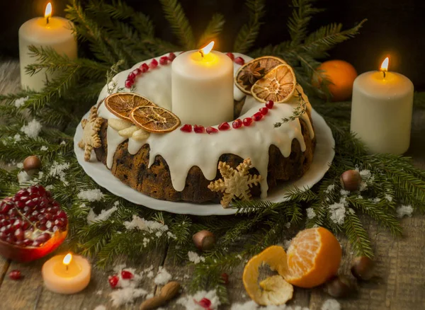 Gâteau aux fruits anglais de Noël avec des fruits confits, des fruits secs et des noix, décoré de glaçage blanc sur un fond en bois avec des branches de sapin, des bougies. Cuisine anglaise festive — Photo