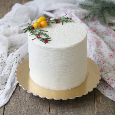Beyaz yeni yıl veya Christmas cake, dal biberiye ve kızılcık ahşap bir masa üzerinde Kamkat ile süslenmiş. Kış dekor. Kışın doğanlar için bir Doğum günü pastası. Kopya alanı, seçici odak
