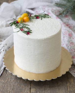 Beyaz yeni yıl veya Christmas cake, dal biberiye ve kızılcık ahşap bir masa üzerinde Kamkat ile süslenmiş. Kış dekor. Kışın doğanlar için bir Doğum günü pastası. Kopya alanı, seçici odak