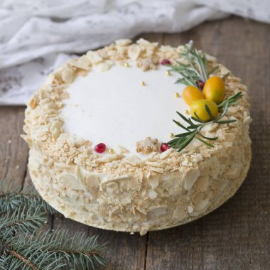 Beyaz yeni yıl veya Noel kek Napoleon, dal biberiye ve kızılcık ahşap bir masa üzerinde Kamkat ile süslenmiş. Kışın doğanlar için bir Doğum günü pastası. Kopya alanı, seçici odak
